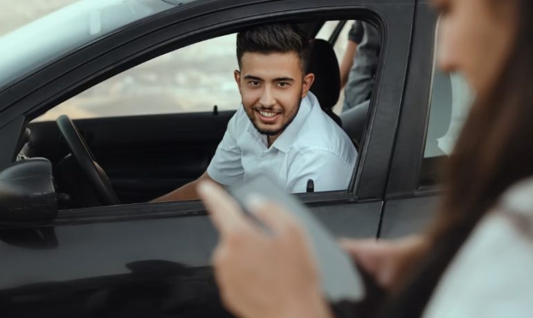 Personne en tenue professionnelle à côté d'une voiture devant un immeuble de bureaux, illustrant le covoiturage domicile-travail
