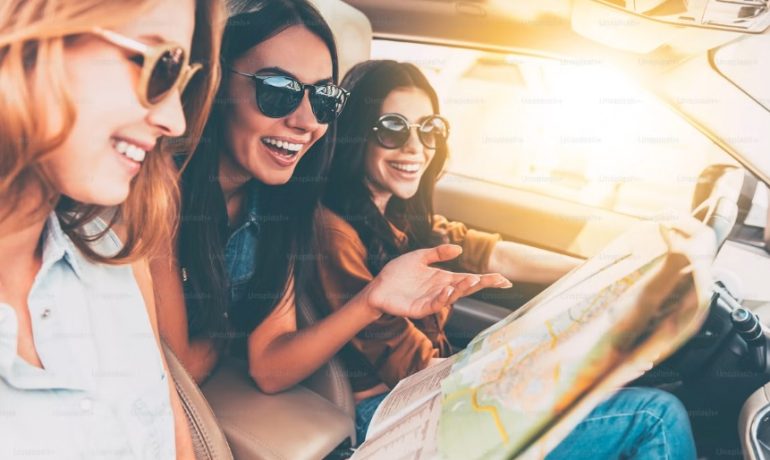 Groupe de femmes souriant à côté d'une voiture, illustrant le service de covoiturage sécurisé et réservé aux femmes