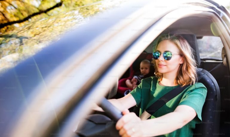 Personne souriante au volant d'une voiture en ville, illustrant le covoiturage quotidien pour des déplacements économiques