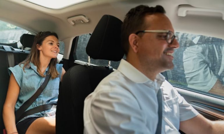 Voiture électrique sur une route bordée d'arbres, illustrant un service de covoiturage écologique et durable